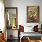 Vintage European couple historical artwork in ornate frame displayed above a classic wooden bed
