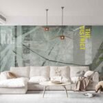 Industrial concrete wallpaper featuring distressed grey textures, urban typography and architectural graphics behind a modern living room sofa
