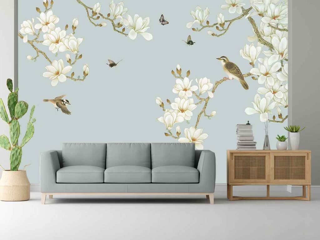 Magnolia bird wallpaper featuring white flowers, flowering branches, birds and butterflies on a soft blue grey background in a modern living room